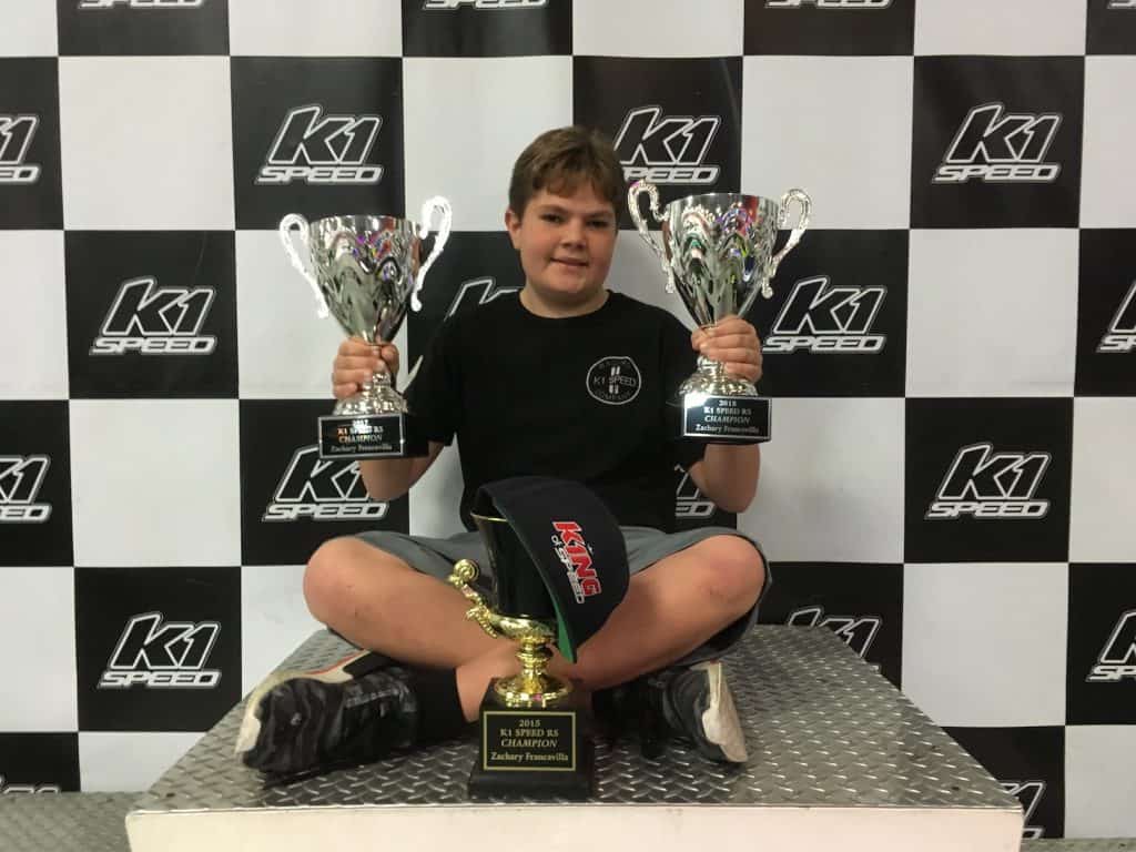Zachary Francavilla sits on the podium at K1 Speed with his trophies
