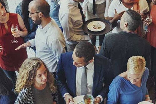 group of company professionals talking and eating at a party