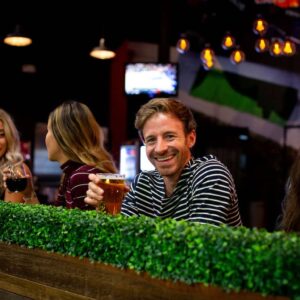 a man holds up a beer and smiles at the paddock lounge inside k1 speed irvine