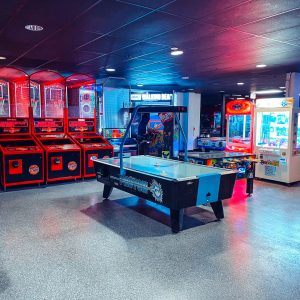 an air hockey table is flanked by basketball hoops and prize machines inside the arcade k1 speed las vegas