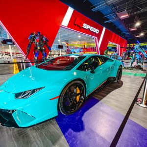 A close shot of a teal Lamborghini in the lobby of K1 Speed Caguas with Transformers and Avatar statues behind it