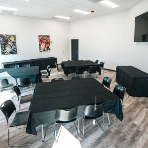 a meeting room inside k1 speed chula vista with tv and automative art on the wall