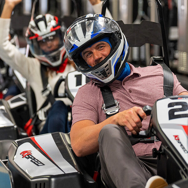 a man in a polo shirt sits in a go kart at k1 speed as part of a corporate event