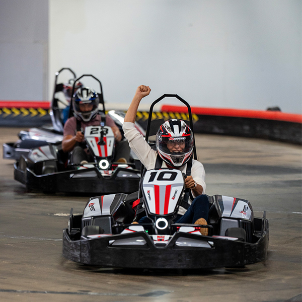 woman cheers while racing go karts at k1 speed during a corporate event