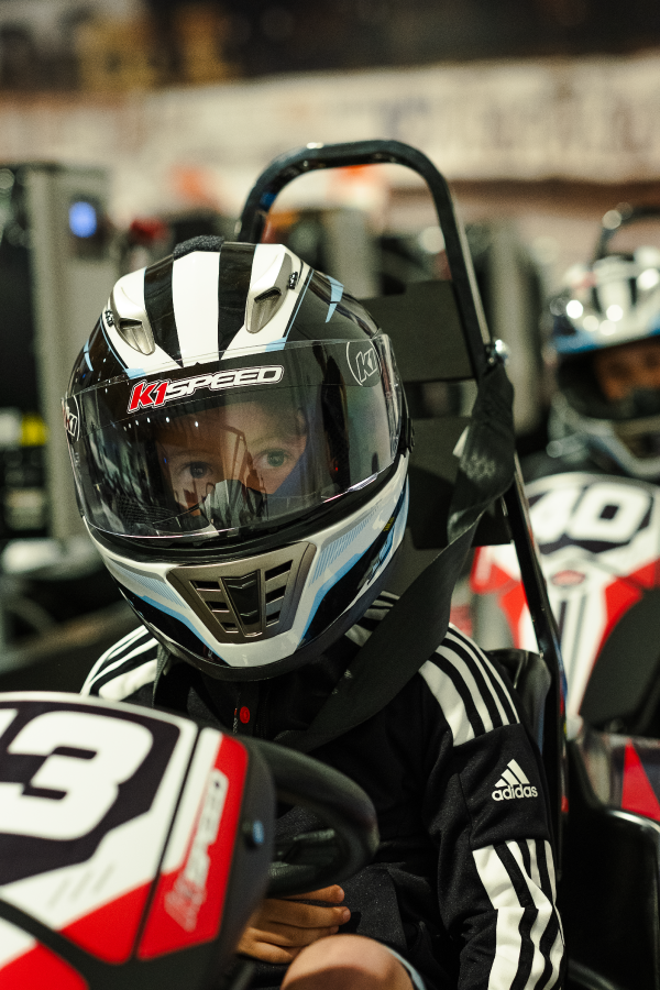 a kid sits in a go-kart as part of a birthday party at k1 speed