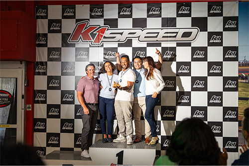 a corporate event group stands on the podium at k1 speed after a company team building event