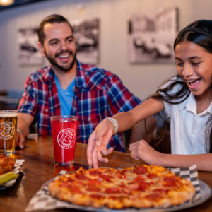 Dad and his daughter sharing pizza and smiles in the Paddock Lounge