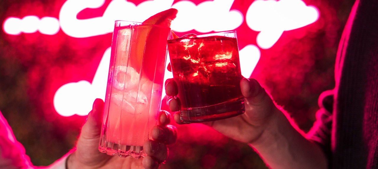 two people clink glasses with cocktails together
