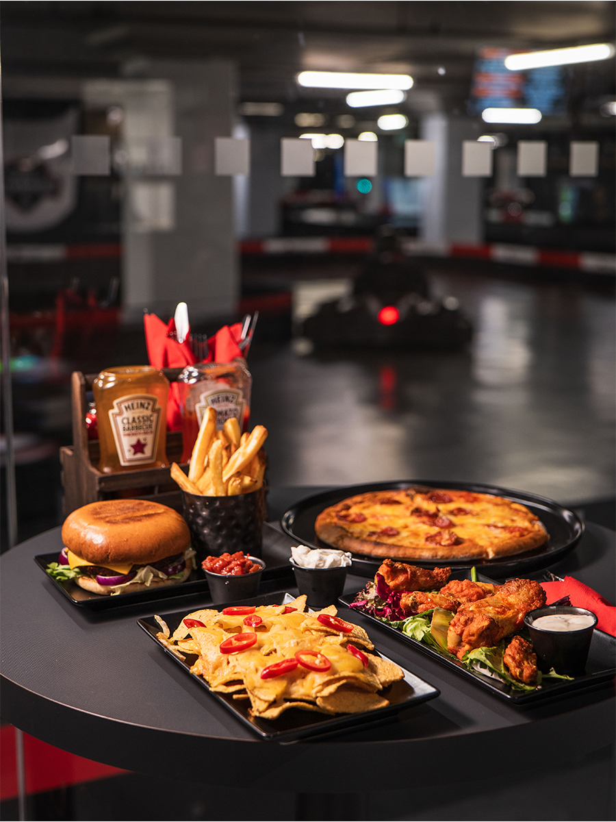 nachos, burger, wings, and pizza on a taable at k1 speed in canary wharf