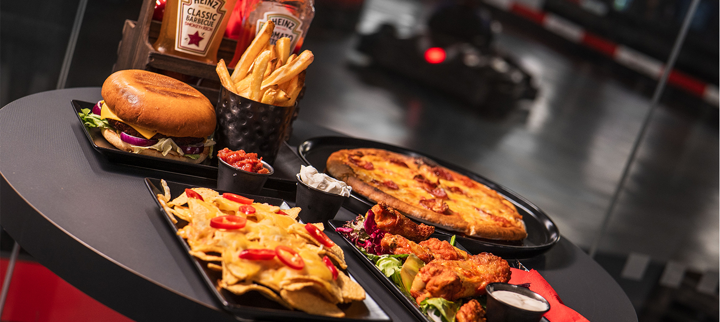 nachos, burger, wings, and pizza on a taable at k1 speed in canary wharf
