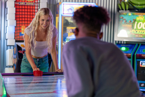 Two teens play air hockey at K1 Speed