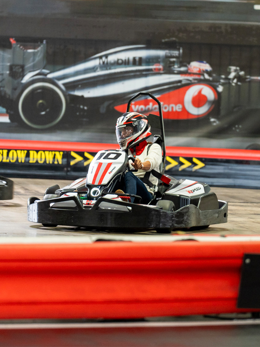 an office worker races a go kart at k1 speed during a corporate event