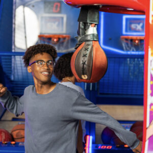 A teen throws a punch at a punching bag arcade game at K1 Speed