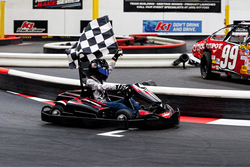 Kid waves checkered flag during victory lap at K1 Speed.
