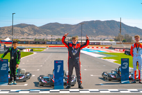 The teen podium finishers stand on track next to their go-karts.